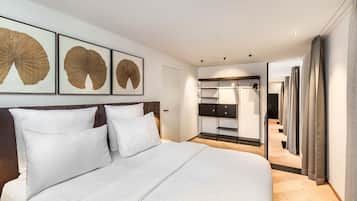 A modern hotel room with a large bed, a walk-in closet, and framed artwork on the wall.