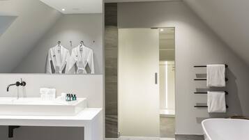 A modern bathroom with a large mirror, white sink, and a bathtub.