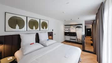 A hotel room with a large bed, a bedside table, a wardrobe, and a mirror.