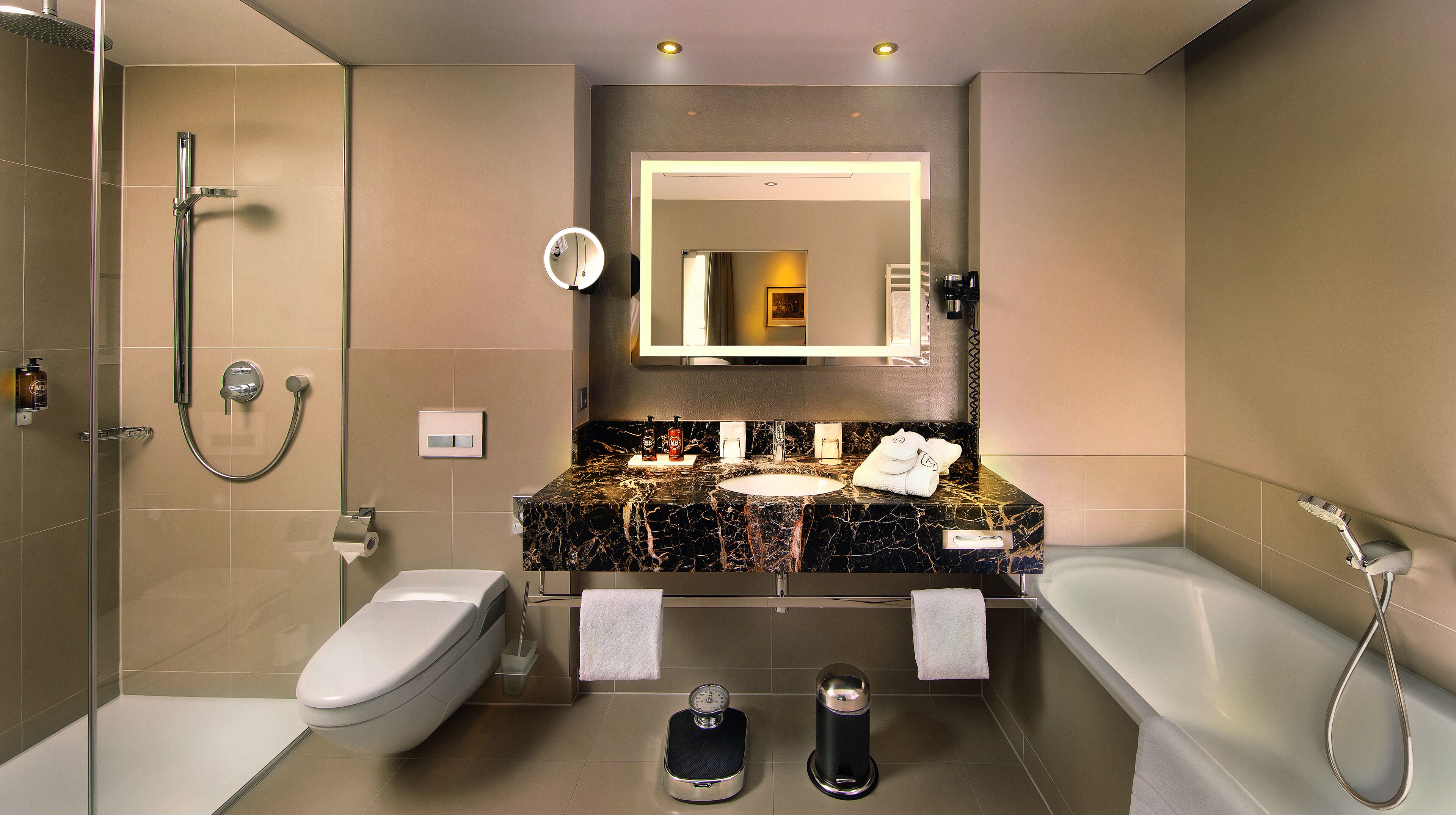 Un baño moderno con lavamanos de mármol, bañera, inodoro y zona de ducha.
