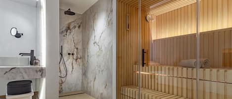 Un baño moderno con pared de mármol, una bañera independiente y una zona de sauna de madera.