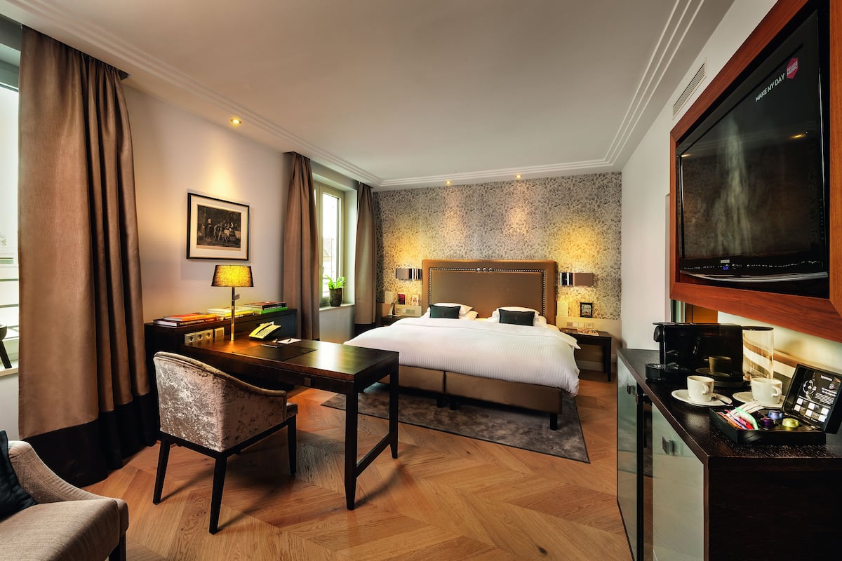 Une chambre d’hôtel équipée d’un lit, d’un bureau, d’une chaise, d’une télévision et offrant une vue sur la ville.