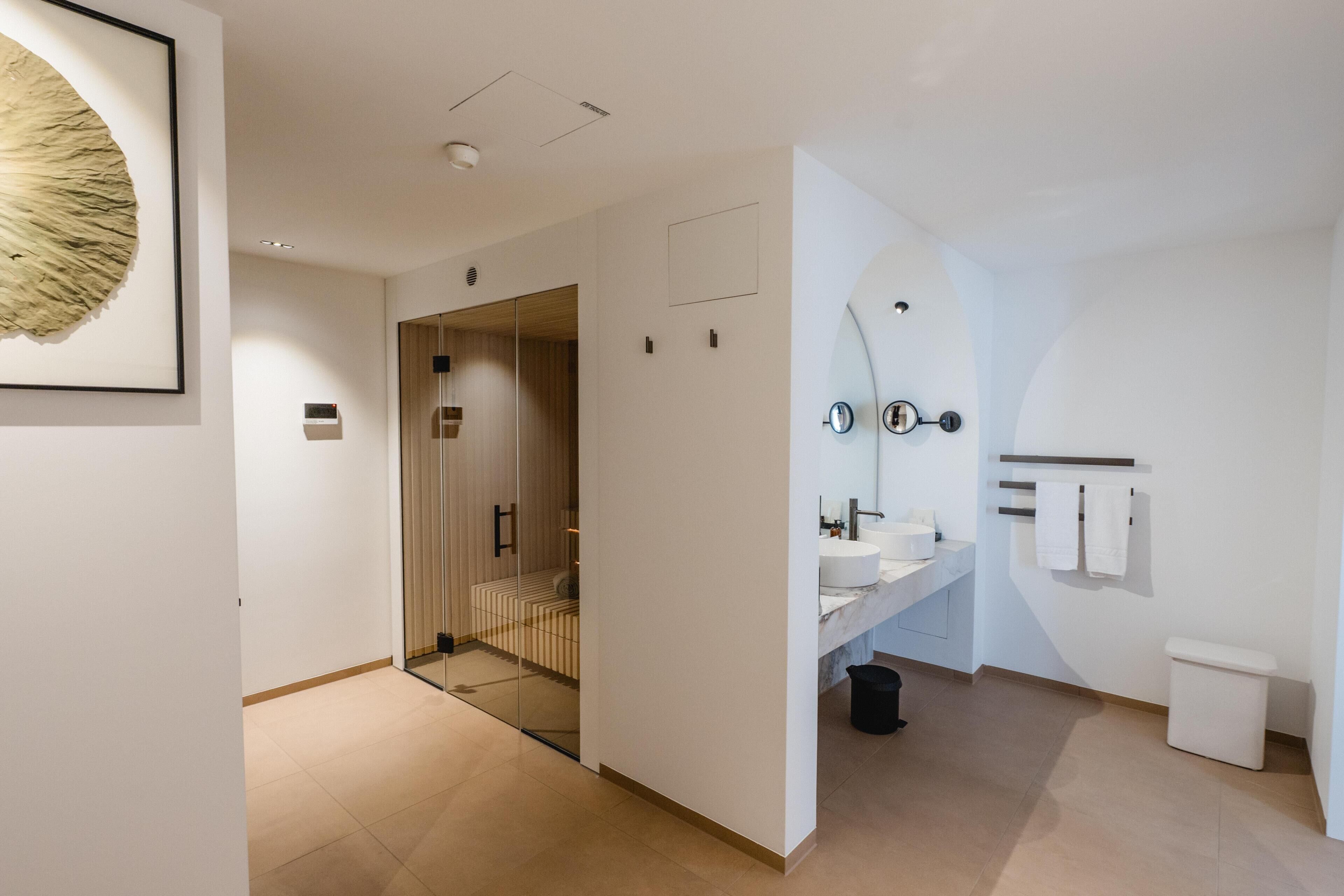 A modern bathroom with a glass shower enclosure, a white sink, and a toilet.
