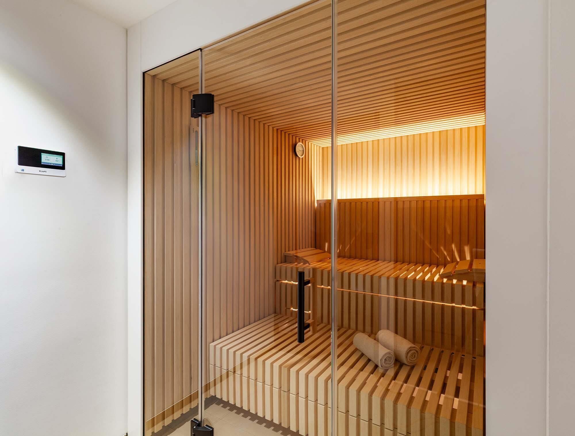 Un sauna con listones de madera, un panel de control y toallas.