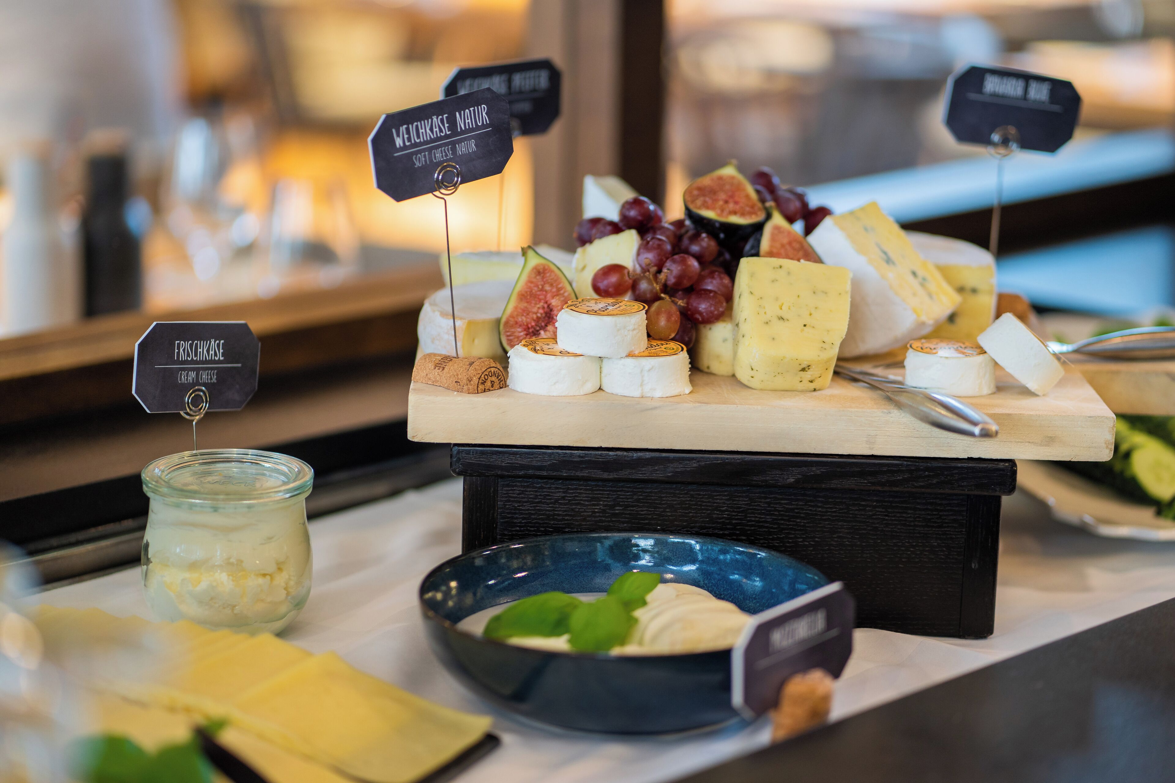 Una tabla de quesos y frutas con etiquetas que identifican distintos tipos de queso.