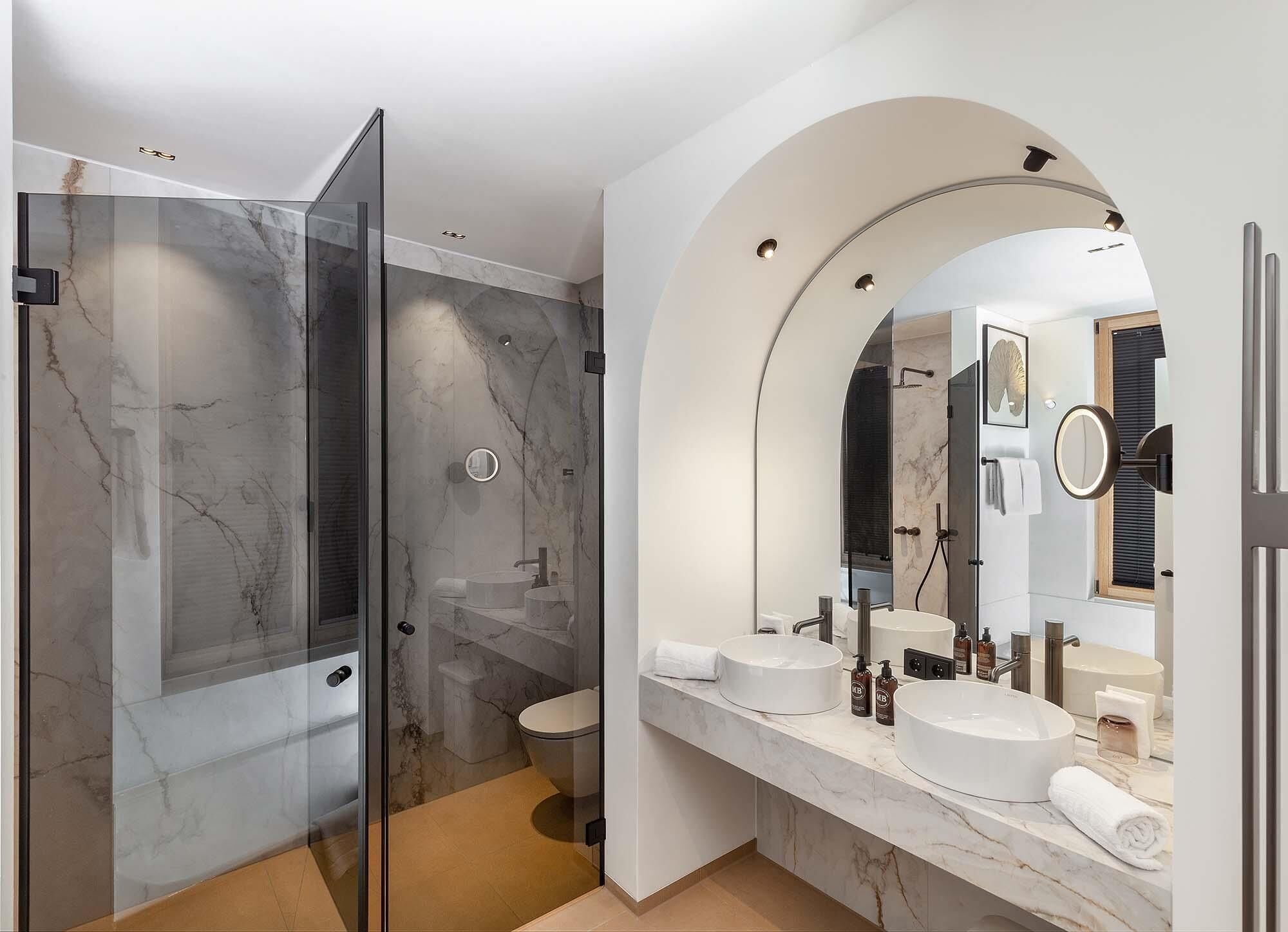 Un baño moderno con ducha de vidrio, tocador doble y un espejo grande.