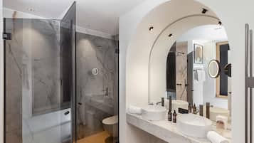 Un baño moderno con ducha de vidrio, tocador doble y un espejo grande.