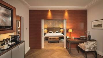 Habitación de hotel con cama, escritorio, silla, cafetera y televisión.