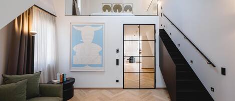 Una sala de estar moderna con un sofá, una mesa de centro, una escalera y una puerta que da a otra habitación.
