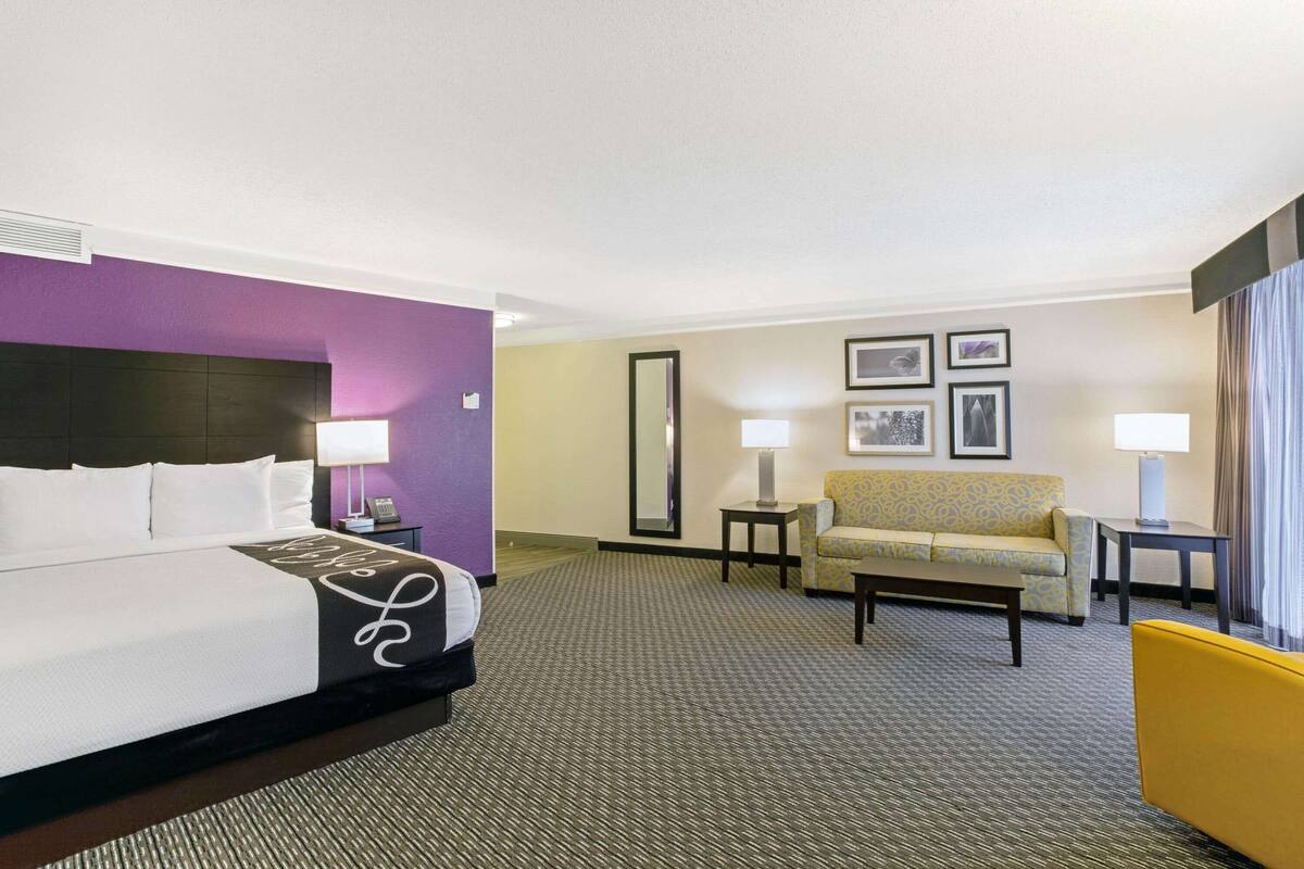 Una camera d'albergo con un letto, un divano, una sedia e una scrivania.