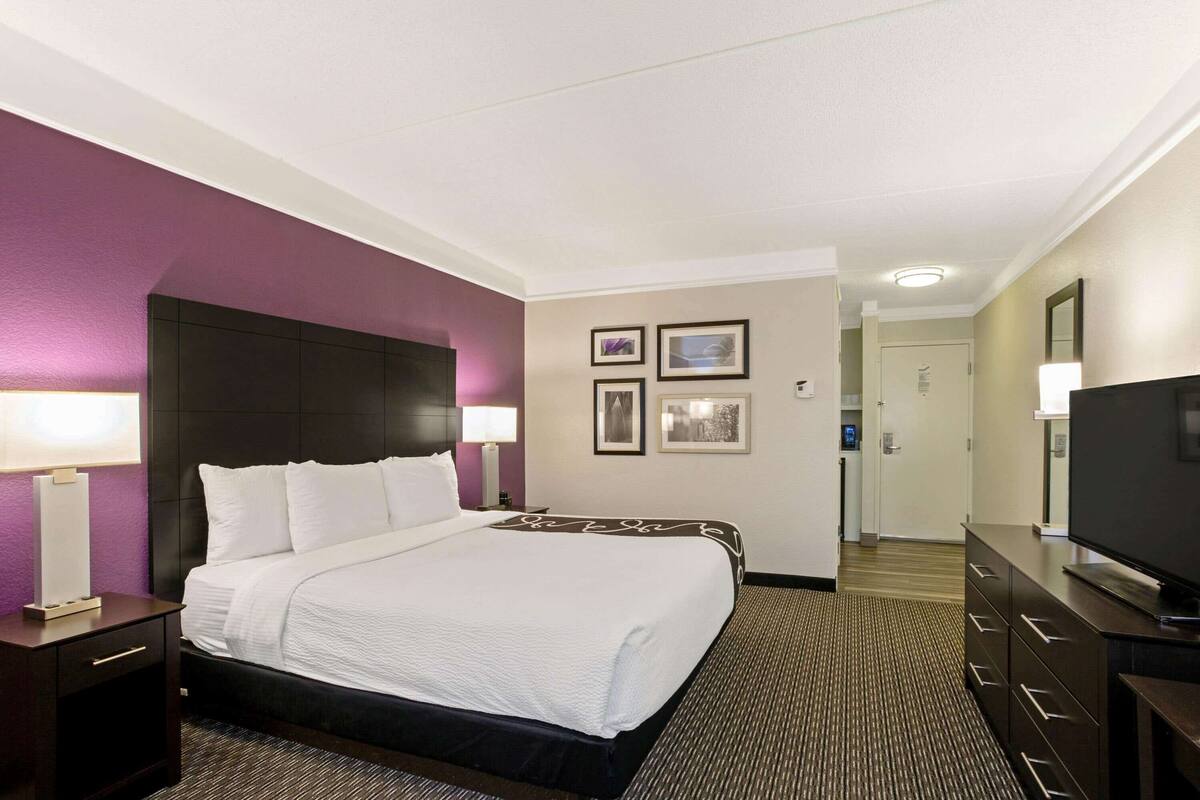 Una camera d'albergo con un letto grande, una TV, una scrivania e una sedia.