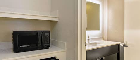 Una kitchenette compacta con microondas, refrigerador pequeño y pileta.