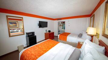 A hotel room with two beds, a TV, a desk, and a mirror.