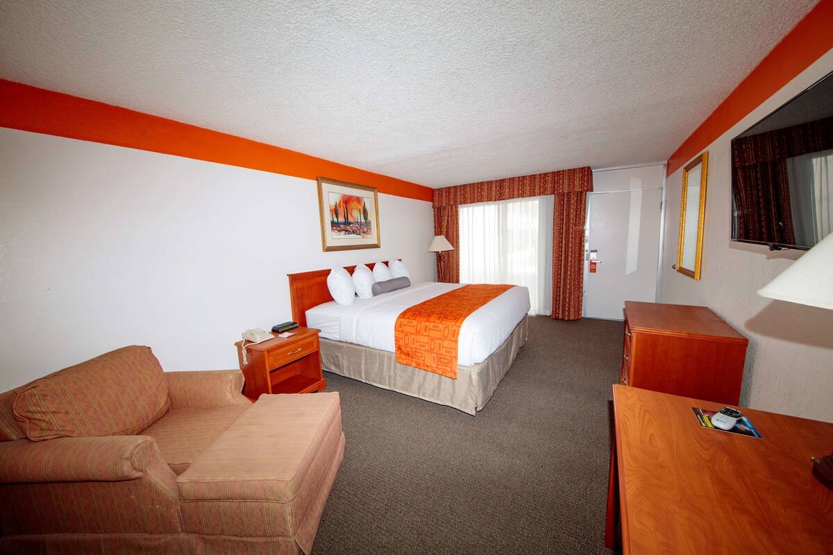 A hotel room with a bed, a sofa, a desk, and a nightstand.