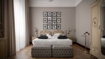 Une chambre avec un grand lit, deux tables de chevet, une armoire et un mur recouvert de tableaux encadrés.