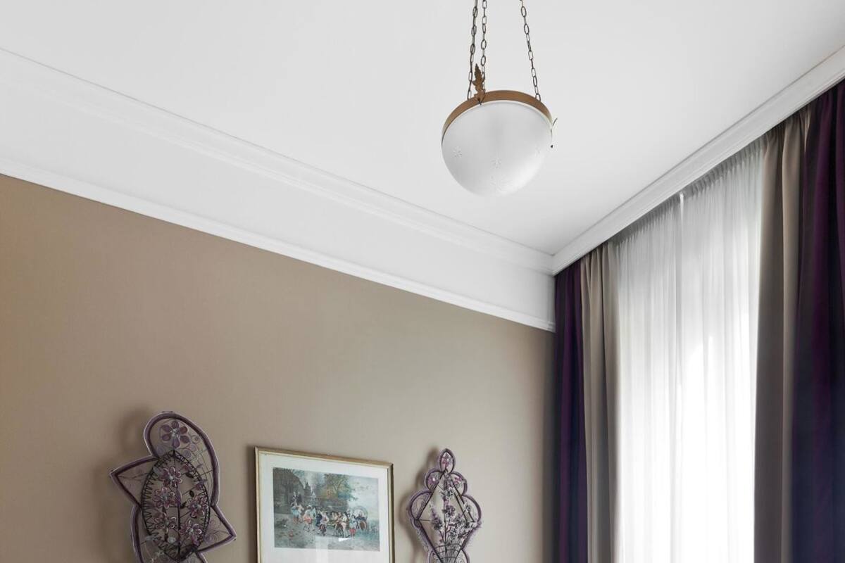 Une chambre à coucher comprenant un lit, une table de chevet, une chaise, une table et un luminaire suspendu.