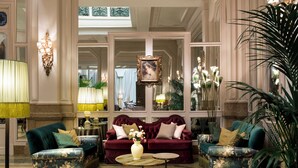 A luxurious lobby with two plush sofas, a round coffee table, and elegant wall sconces.
