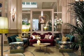 A luxurious lobby with two plush sofas, a round coffee table, and elegant wall sconces.