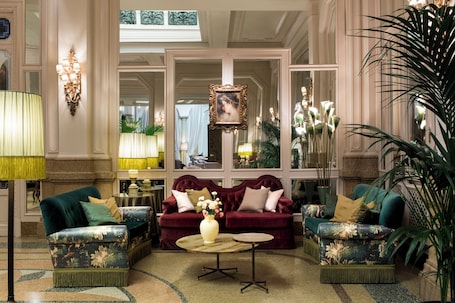 A luxurious lobby with two plush sofas, a round coffee table, and elegant wall sconces.