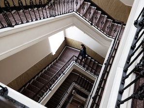 A multi-level interior with a staircase featuring ornate black railings and patterned carpeted steps.