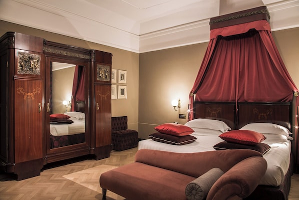 A bedroom with a four-poster bed, a large mirror, and a red canopy.