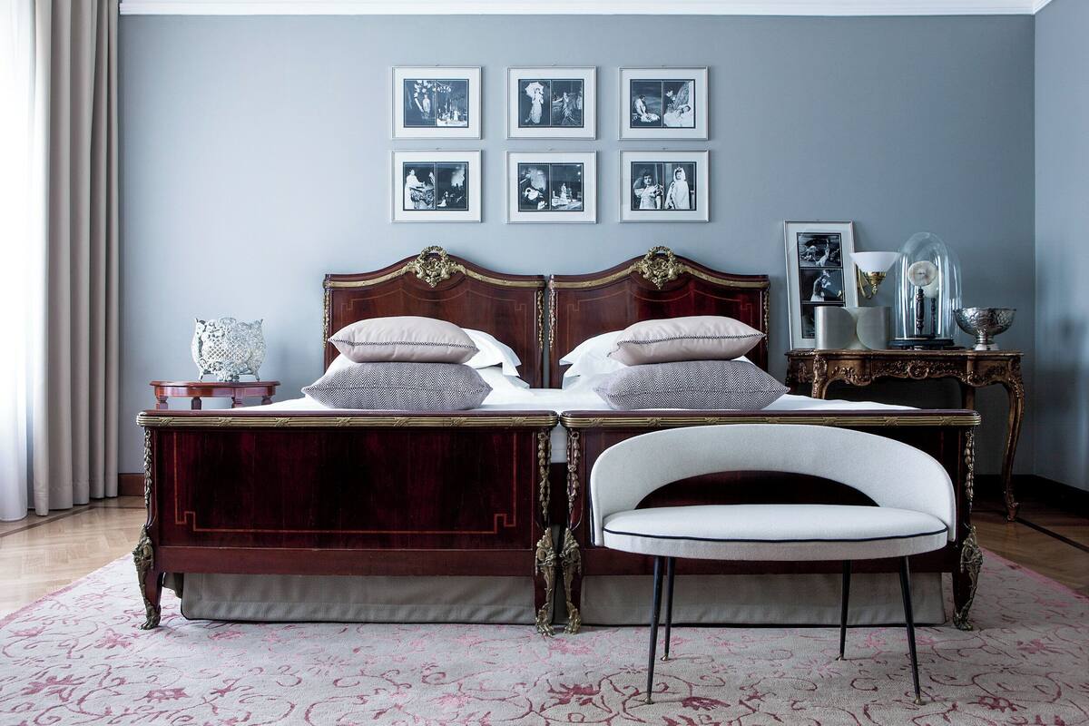 A bedroom with a double bed, two bedside tables, a chair, and framed pictures on the wall.