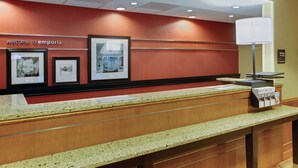 A reception desk with framed pictures on the wall, a welcome sign, and a manager's office sign. - Hampton Inn Emporia (Emporia)