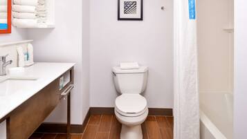 Een badkamer met toilet, wastafel en douchegordijn.