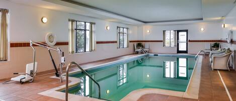 A large indoor swimming pool with a clear view of the pool area, including a pool chair and a wheelchair.