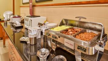 Un bufé con diversas opciones de comida, incluyendo revuelto de carne, salchicha y otros platos.