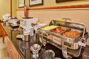 A buffet with various food options including corn beef hash, sausage, and other dishes.