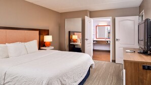 A hotel room with a large bed, a bedside table with a lamp, a TV, and a wardrobe. - Hampton Inn Emporia (Emporia)