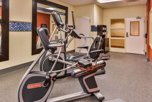 A gym with elliptical machines and a wall-mounted mirror.