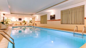 A swimming pool with a clear blue water, surrounded by white lounge chairs and a small table. - Hampton Inn Emporia (Emporia)