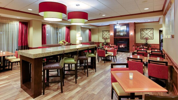 A hotel lobby with a bar area, multiple dining tables, and chairs. - Hampton Inn Emporia (Emporia)