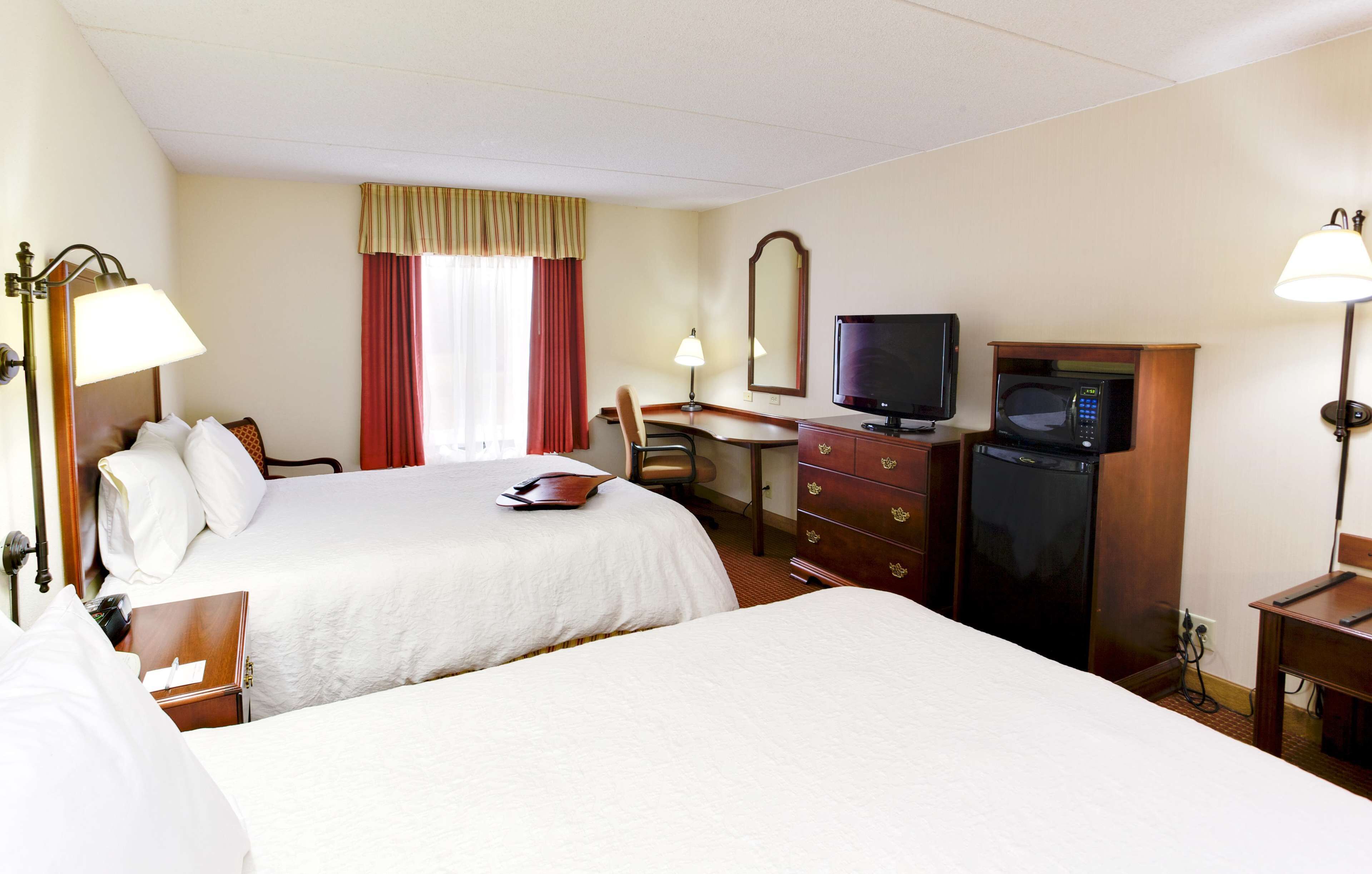 Habitación de hotel con dos camas, un escritorio, televisor, microondas y cómoda.
