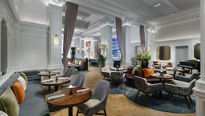 A spacious lobby with seating areas, a grand piano, and a bar.