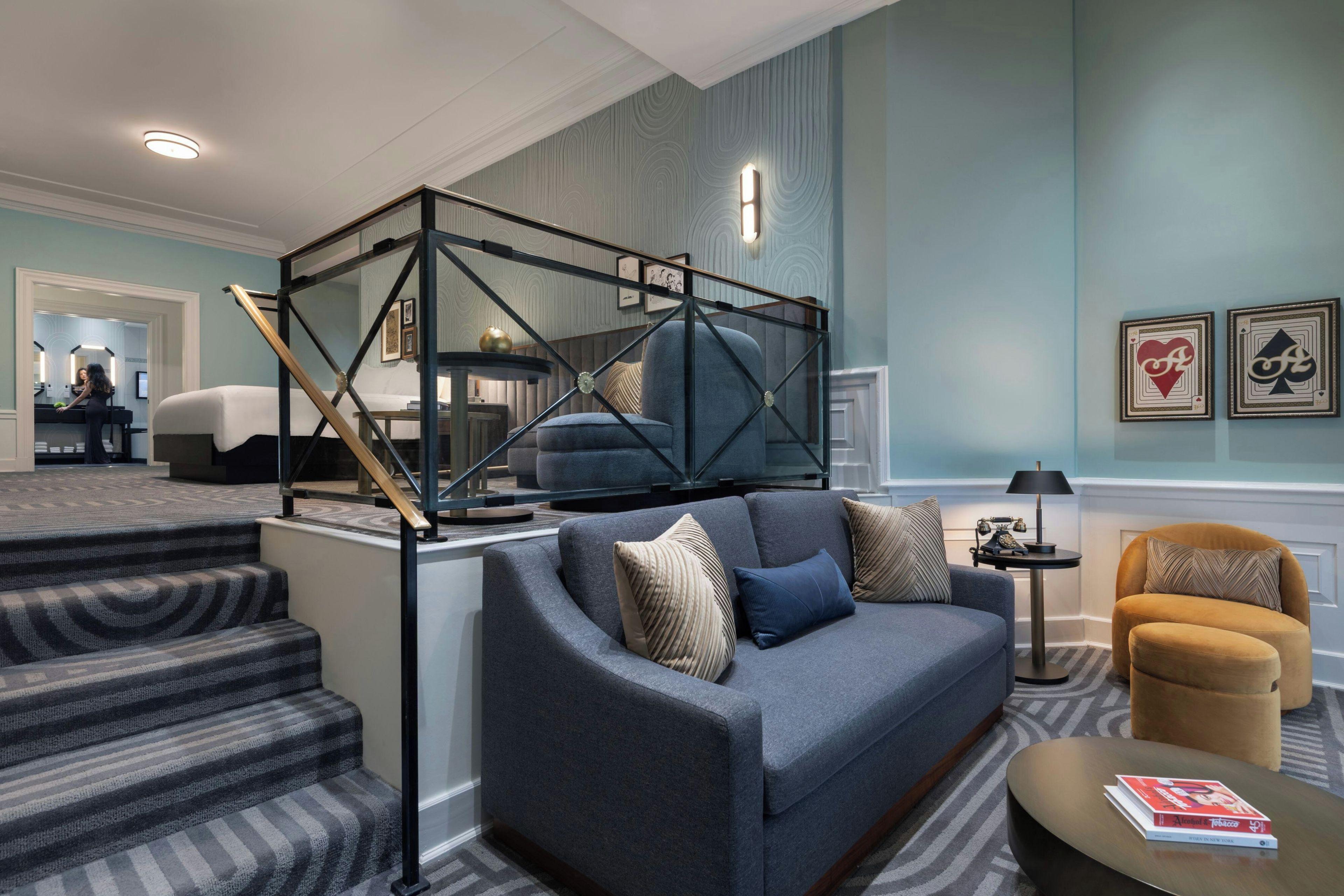Ein modernes Wohnzimmer mit einem grauen Sofa, einem Couchtisch und einer Treppe mit Streifenmuster.