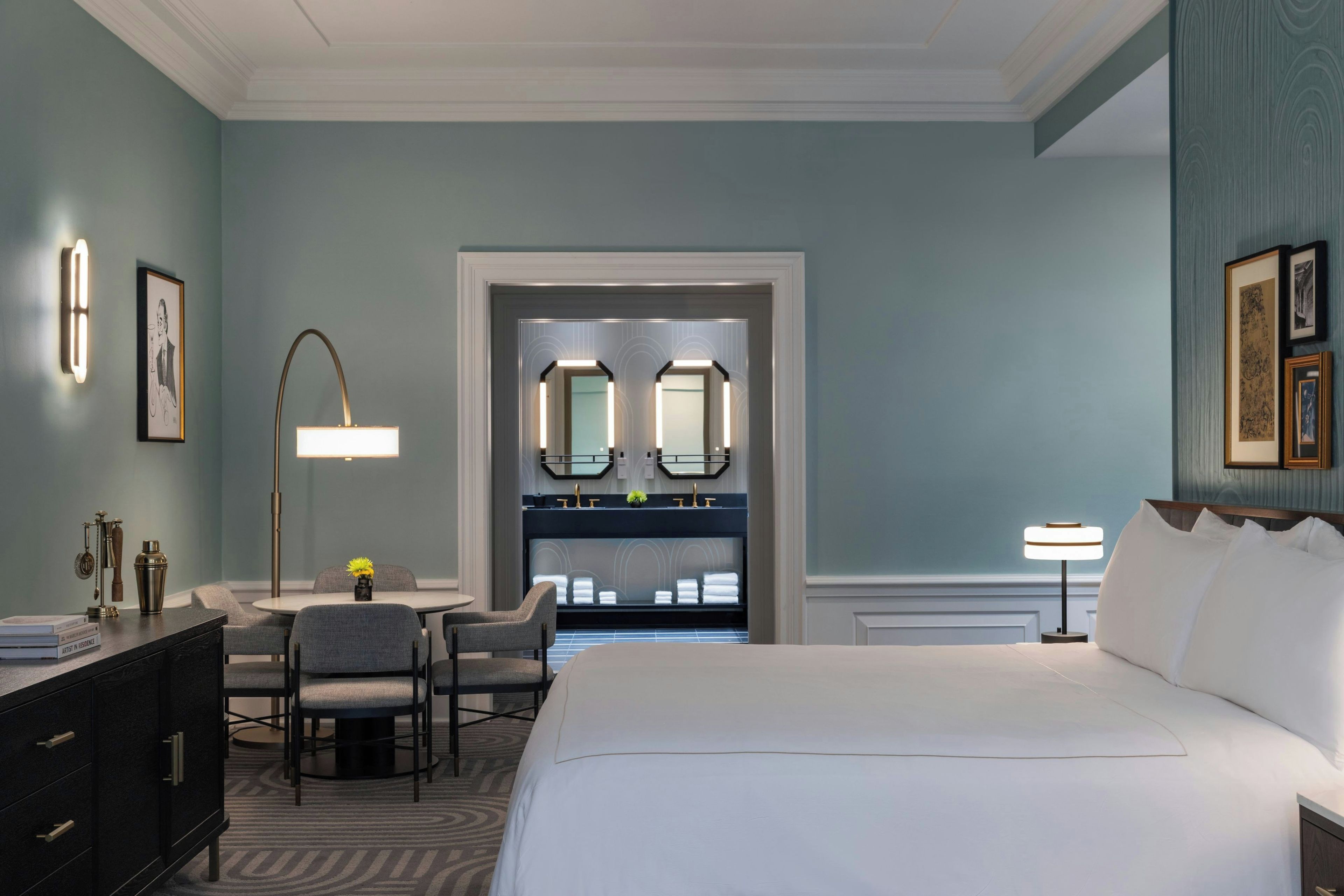 Ein Hotelzimmer mit einem Bett, einem Schreibtisch mit Stuhl, einem Schminktisch mit Spiegeln und einer Kommode.