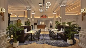 A hotel lobby with a reception desk, seating area, and decorative lighting.