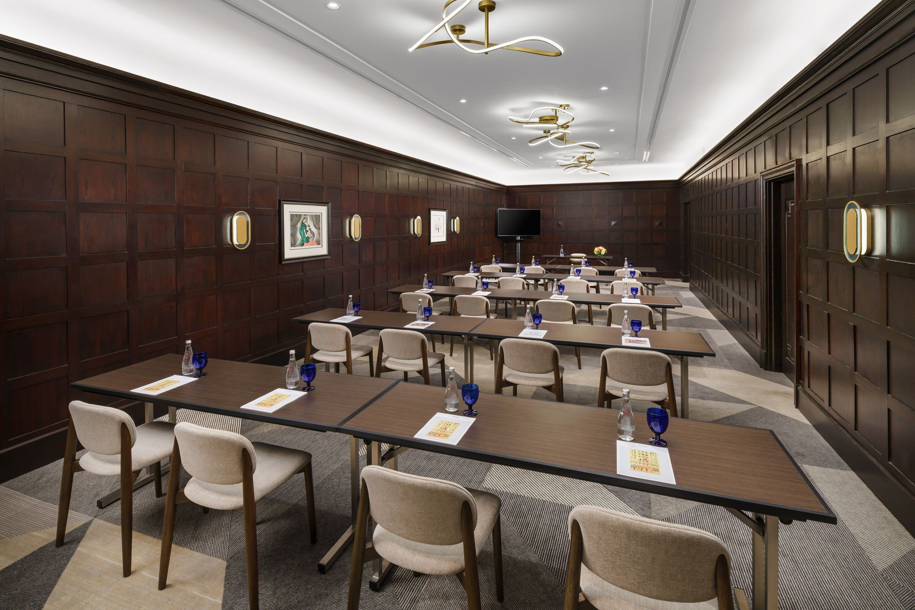 A conference room with multiple tables and chairs, equipped with water bottles and nameplates.
