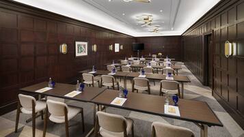 A conference room with multiple tables and chairs, equipped with water bottles and nameplates.
