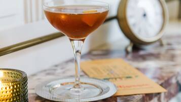 Een martini glas op een marmeren tafel, met een klok en een menukaart op de achtergrond.