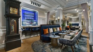 A bar area with a blue-lit shelf, a large clock, and seating with blue and white patterned chairs.