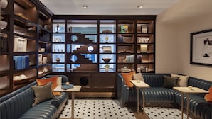 A modern library with leather seating, bookshelves, and decorative items.