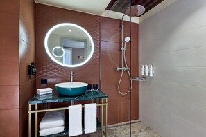 A modern bathroom with a round mirror, a blue sink, and a shower.