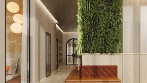 A modern lobby with a green vertical garden, a brown leather bench, and a glass wall with a seating area. - Flesslers Lenggries, a Tribute Portfolio Hotel (Lenggries)