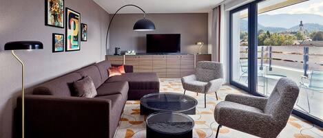 Un salon moderne avec un canapé, des fauteuils, une table basse et un téléviseur.