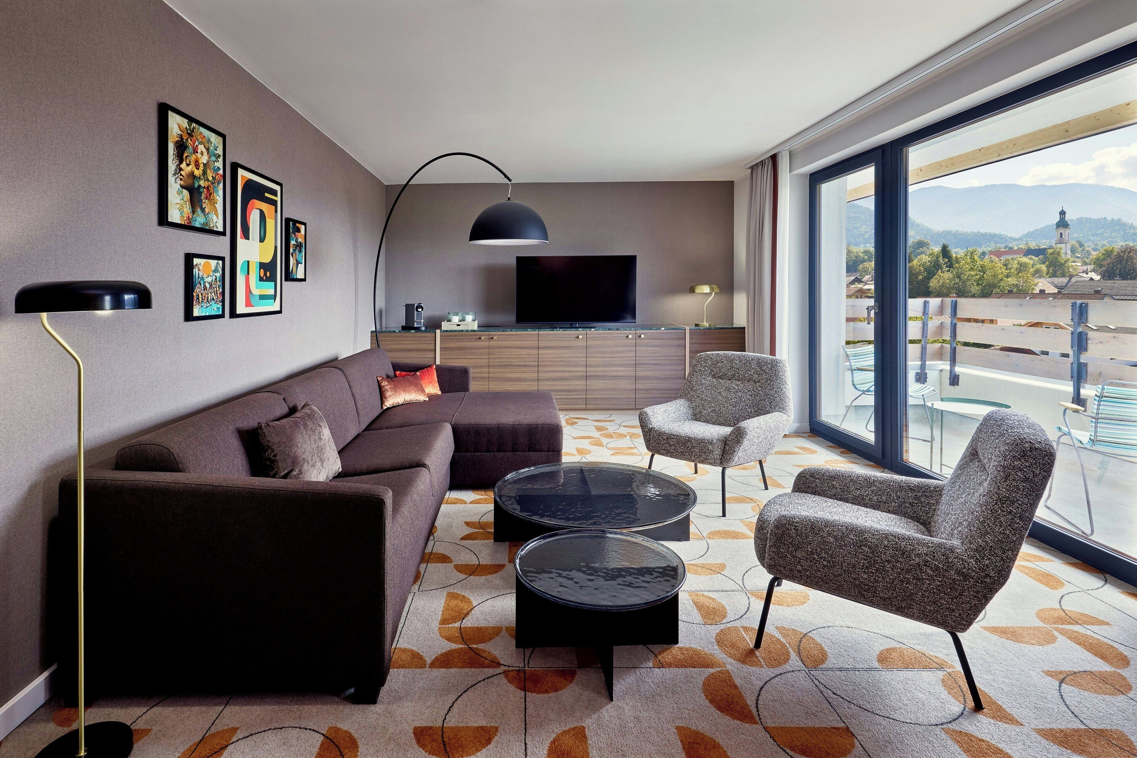 A modern living room with a sofa, two armchairs, a coffee table, and a TV.