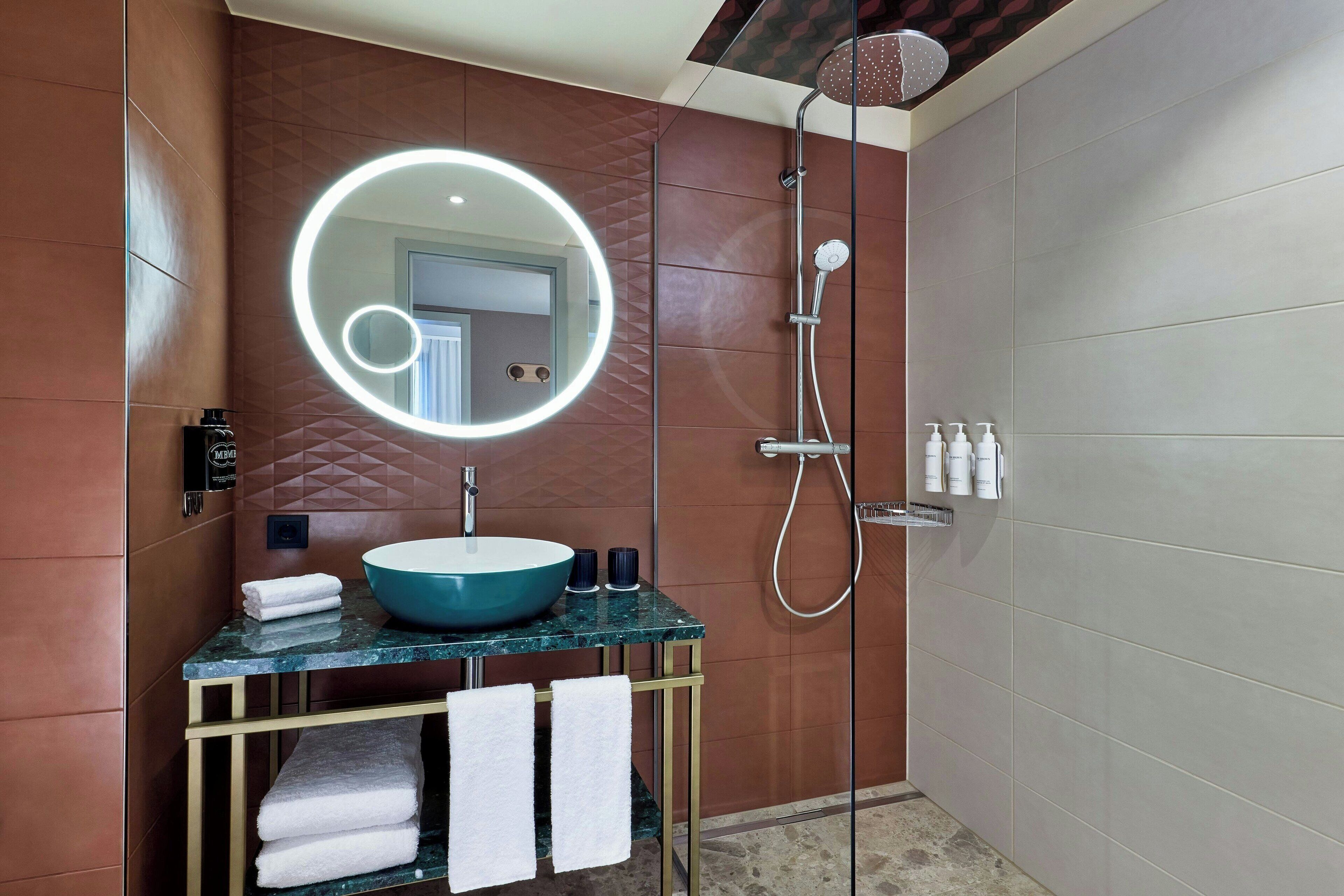 Une salle de bain avec un miroir rond, un lavabo et une douche.